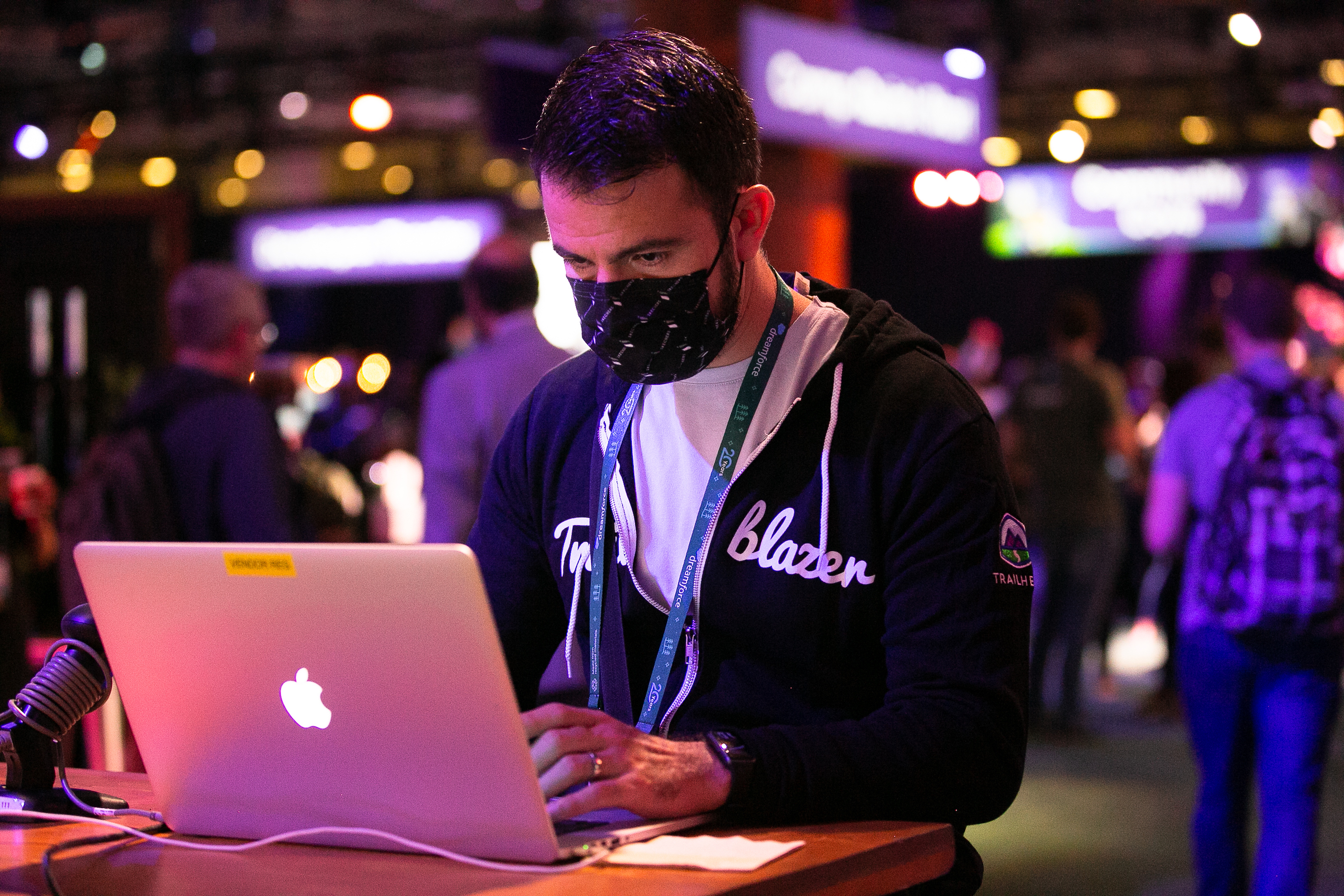A man wearing a mask uses a computer at a Dreamforce 2022 event. 