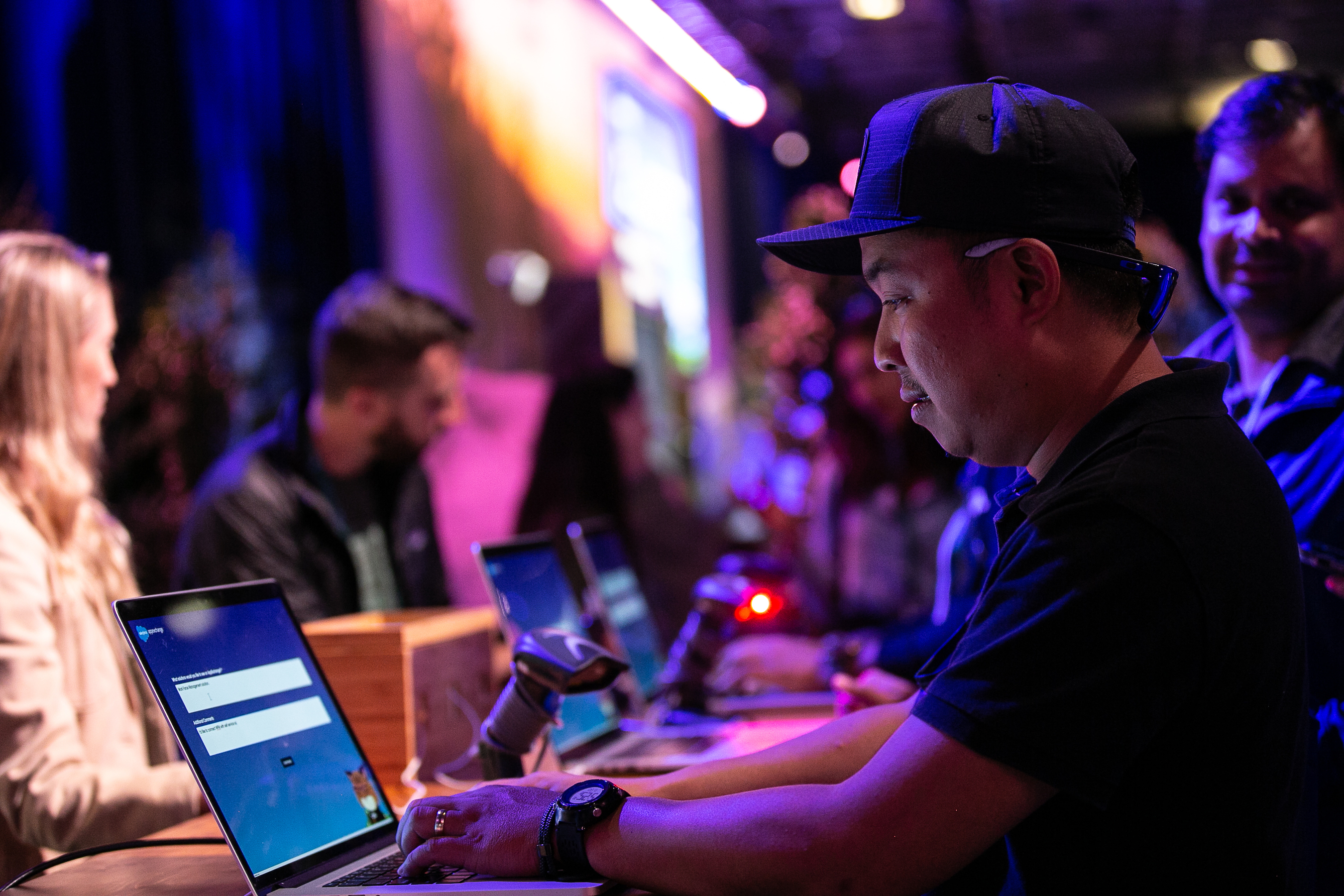 A man wearing a black baseball cap uses a laptop at Dreamforce 2022. 